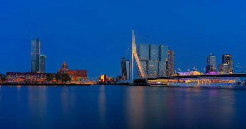 Illuminated buildings in city against clear blue sky