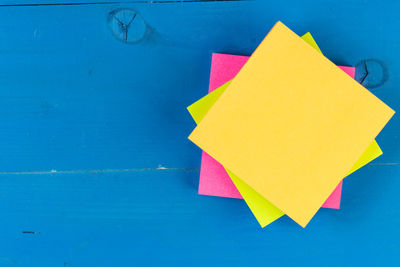 Close-up of yellow paper against blue wall