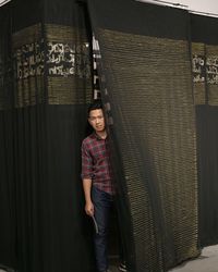 Portrait of young man standing against curtain