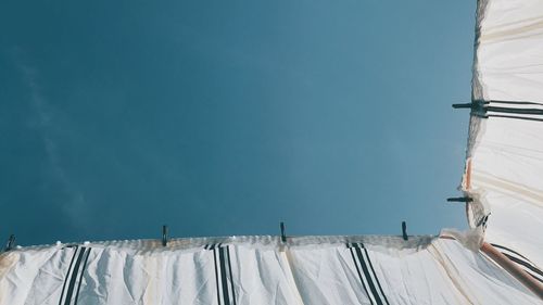 Low angle view of electricity pylon against blue sky