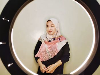 Portrait of young woman standing in mirror