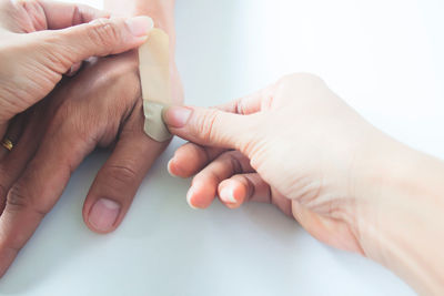 Cropped woman applying bandage on man hand