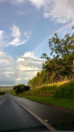 Road by trees against sky