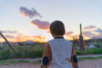 Rear view of toddler standing against sky