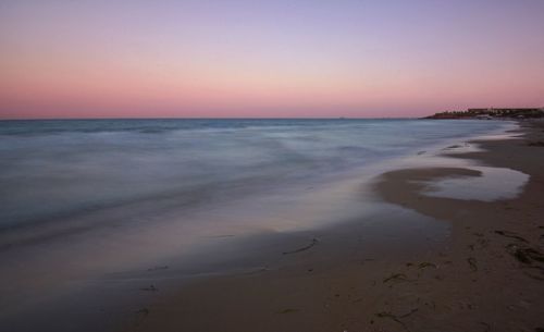 Scenic view of beach against clear sky during sunset