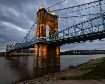Low angle view of bridge over river against sky at dusk