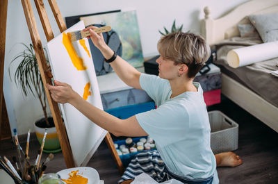 Young woman artist is painting at home in a creative studio setting.