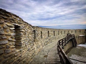 Footpath by wall against sky