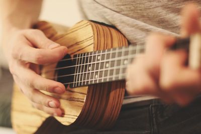 Midsection of man playing guitar