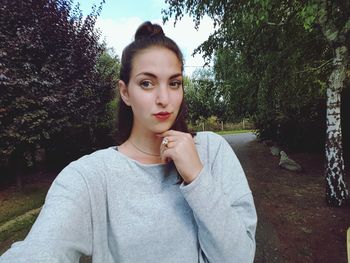 Portrait of young woman against trees