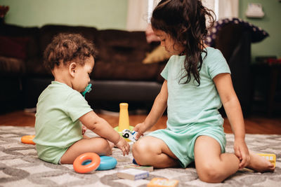 Cute sibling playing with toy at home