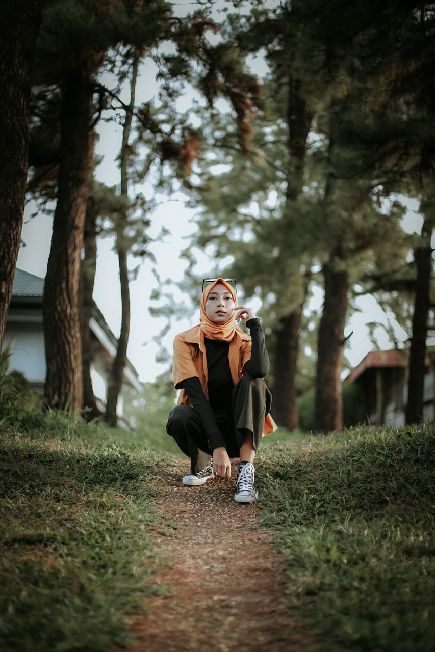 plant, adult, tree, full length, one person, women, nature, lifestyles, autumn, sunlight, clothing, front view, leisure activity, emotion, young adult, outdoors, spring, female, day, happiness, casual clothing, selective focus, land, forest, looking, smiling