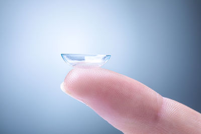 Close-up of hand holding glass against blue background