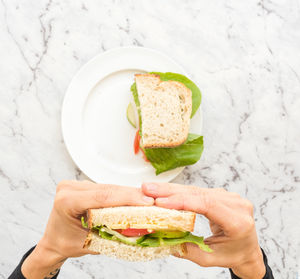 Cropped hands of woman holding sandwich