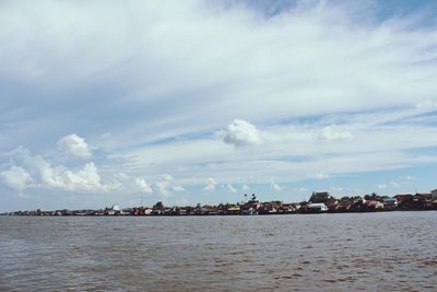 Scenic view of sea by townscape against sky