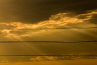 Low angle view of power lines against sky during sunset