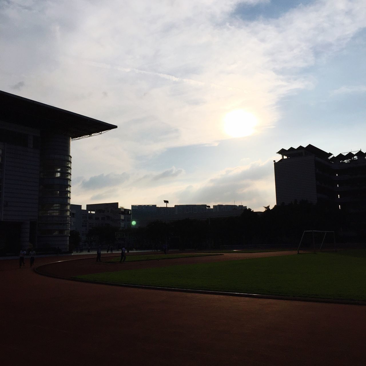 building exterior, architecture, built structure, sun, sky, sunset, city, cloud, lawn, outdoors, cloud - sky, city life, footpath, town, bright, tranquility, no people