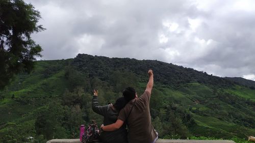 Rear view of men on mountain against sky