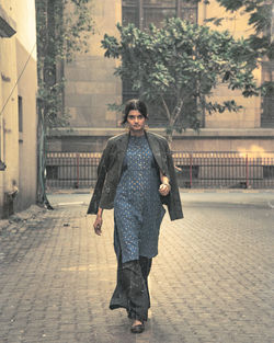 Full length portrait of smiling man walking on street in city