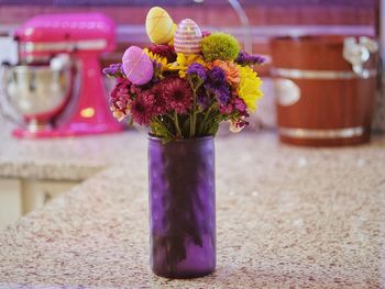 Close-up of purple flower pot on table with purple and pink artificial flowers 