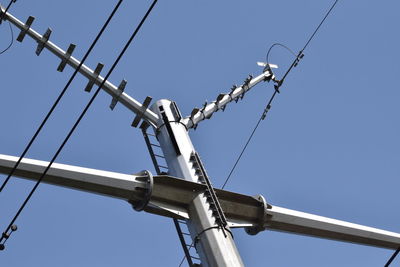 Low angle view of power lines against clear blue sky