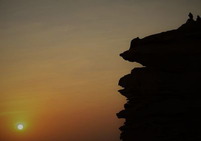 Silhouette rock formations against sky during sunset