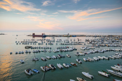 High angle view of sailboats moored in sea against sky during sunset