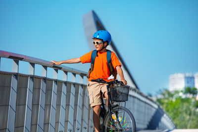 Low angle view of man riding bicycle against clear blue sky