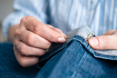 Midsection of woman stitching jeans