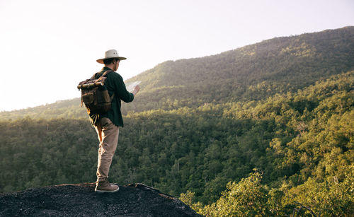 Man standing by tree on mountain against sky