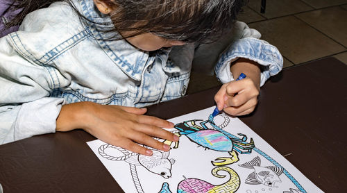 High angle view of girl sitting on wall