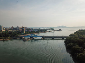 Bridge over river in city against sky