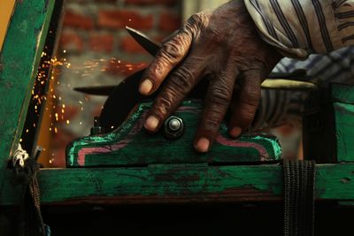 Close-up of man sharpening scissors on spinning metallic wheel