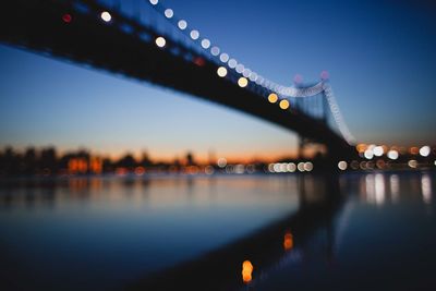 Defocused image of illuminated bridge over river at night