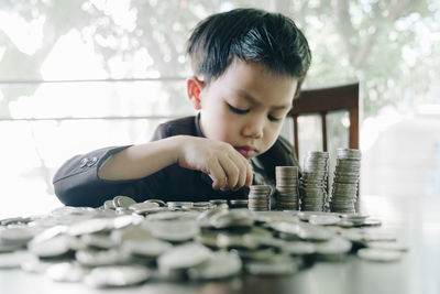 Cute boy stacking coins on table