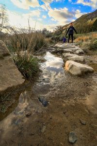 Man on rocks by land against sky