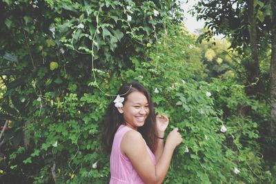 Portrait of smiling young woman against plants