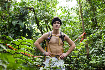 Portrait of smiling shirtless young man standing against plants