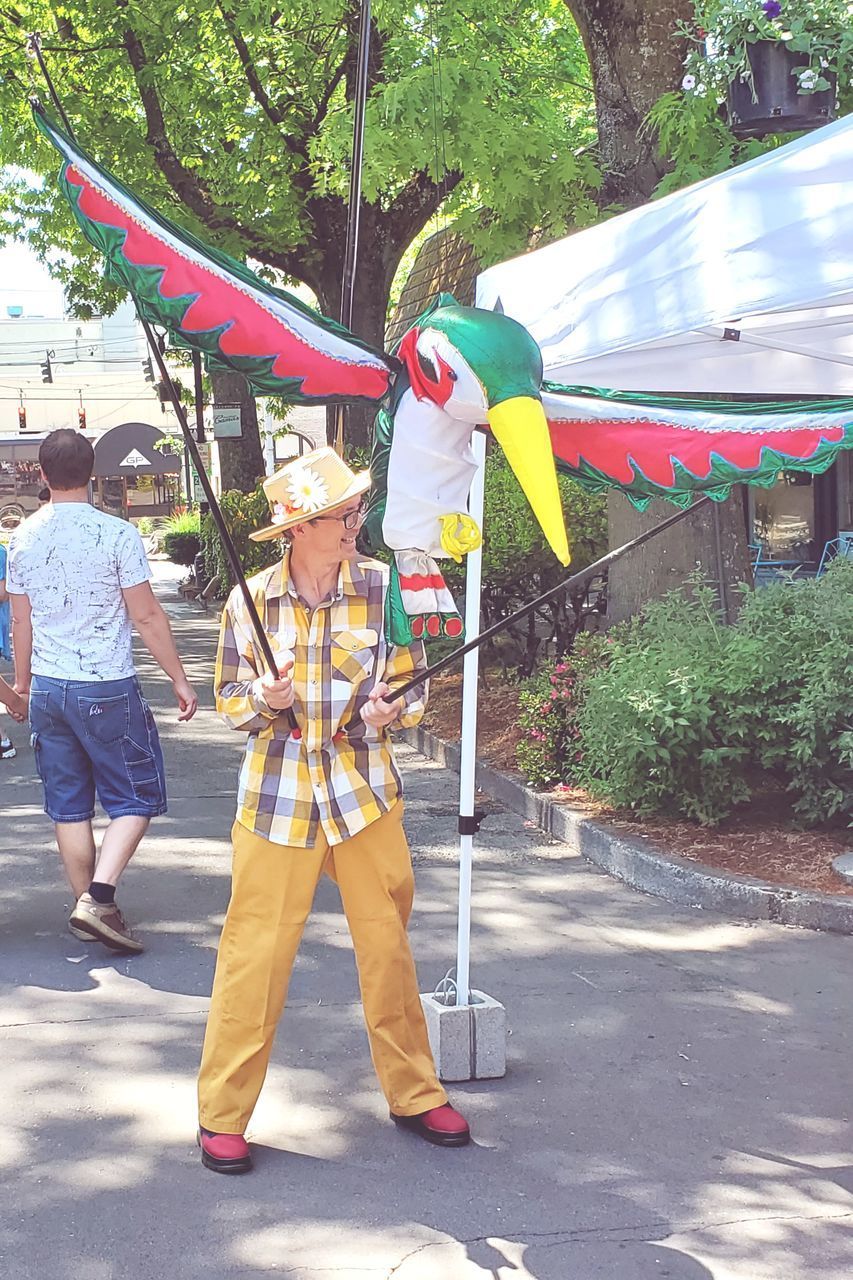 REAR VIEW OF SIBLINGS HOLDING UMBRELLA ON STREET