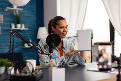 Woman wearing headphones doing podcast in office