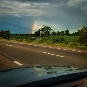 Rainbow over road seen through car windshield