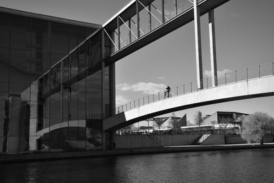 Bridge over river by buildings against sky