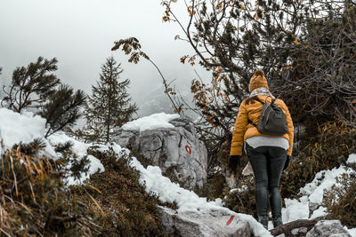 Rear view of woman on snowy hiking trail in misty mountains in winter