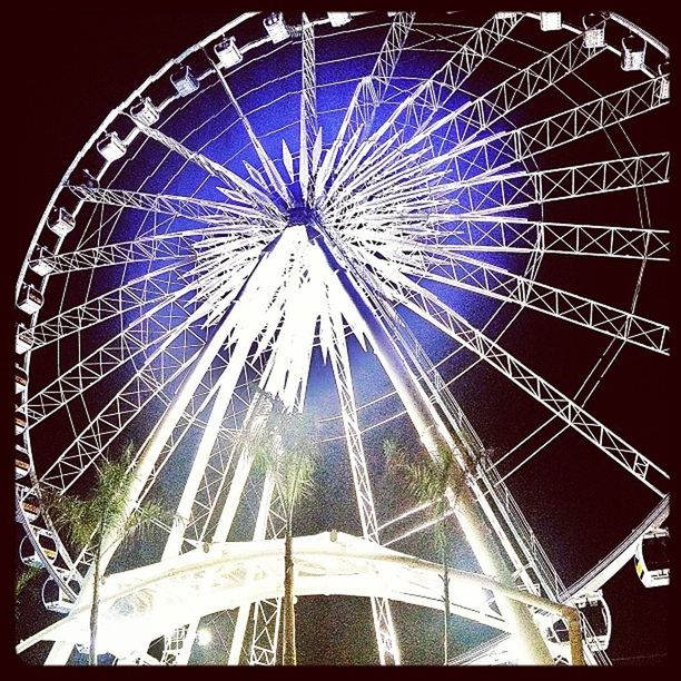 low angle view, ferris wheel, amusement park, arts culture and entertainment, amusement park ride, built structure, architecture, building exterior, sky, outdoors, tall - high, tower, clear sky, no people, night, large, blue, metal, tree