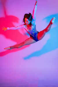 Low angle view of woman with arms raised against blue background