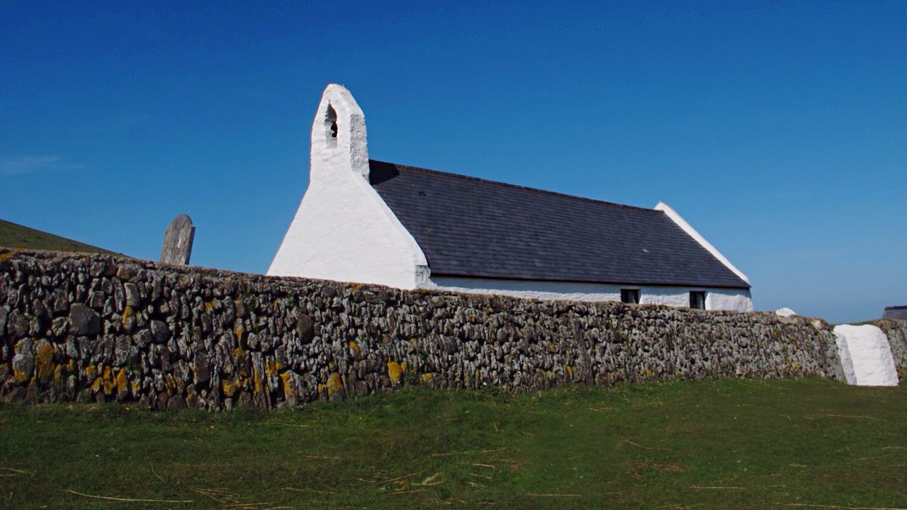 clear sky, blue, built structure, copy space, grass, architecture, building exterior, field, sunlight, landscape, sky, day, outdoors, nature, rural scene, roof, grassy, house, low angle view, no people