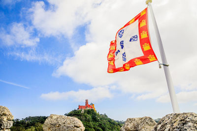 Low angle view of flag on rock against sky