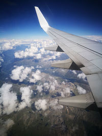 Cropped image of airplane flying over mountains against clear sky