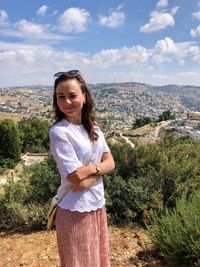 Portrait of smiling woman standing on mountain against sky