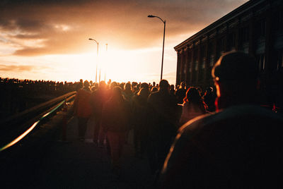 People on street in city against sky during sunset